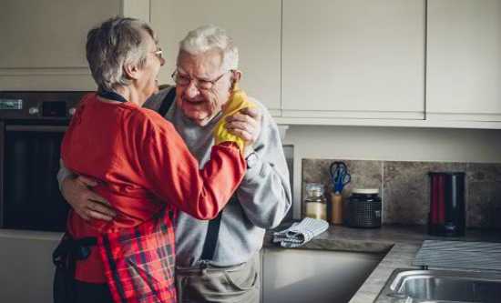 An older couple dance together in a kitchen